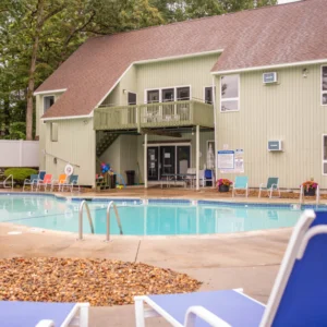Outdoor pool with chairs and green building.