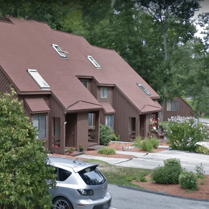 Brown houses with car and greenery.